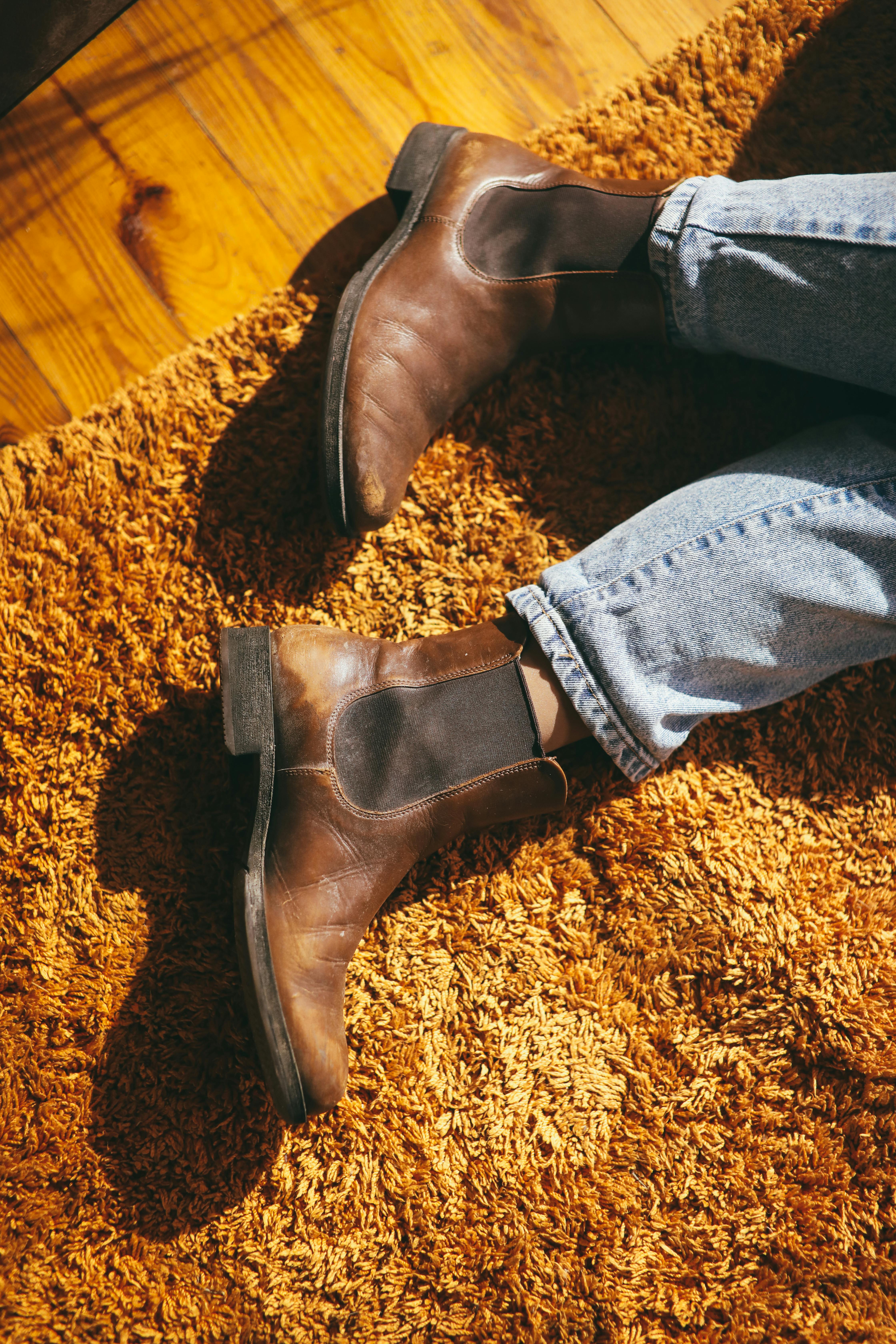 person wearing blue denim jeans and brown leather boots