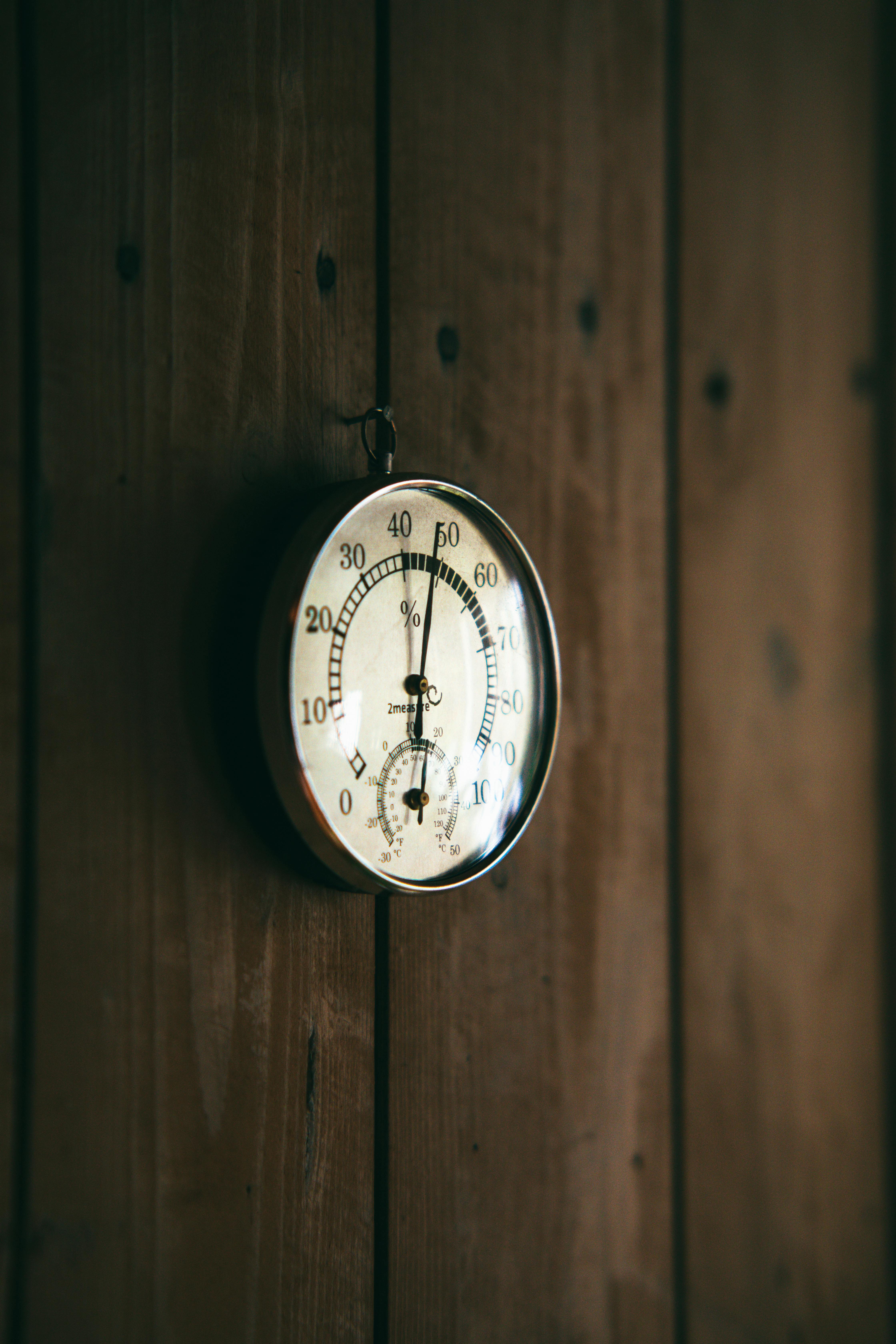 A classic round thermometer mounted on a rustic wooden wall captures a cozy, vintage ambiance.
