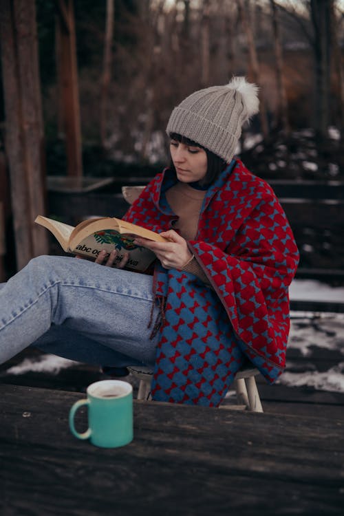 
A Woman Covered in a Blanket Reading a Book