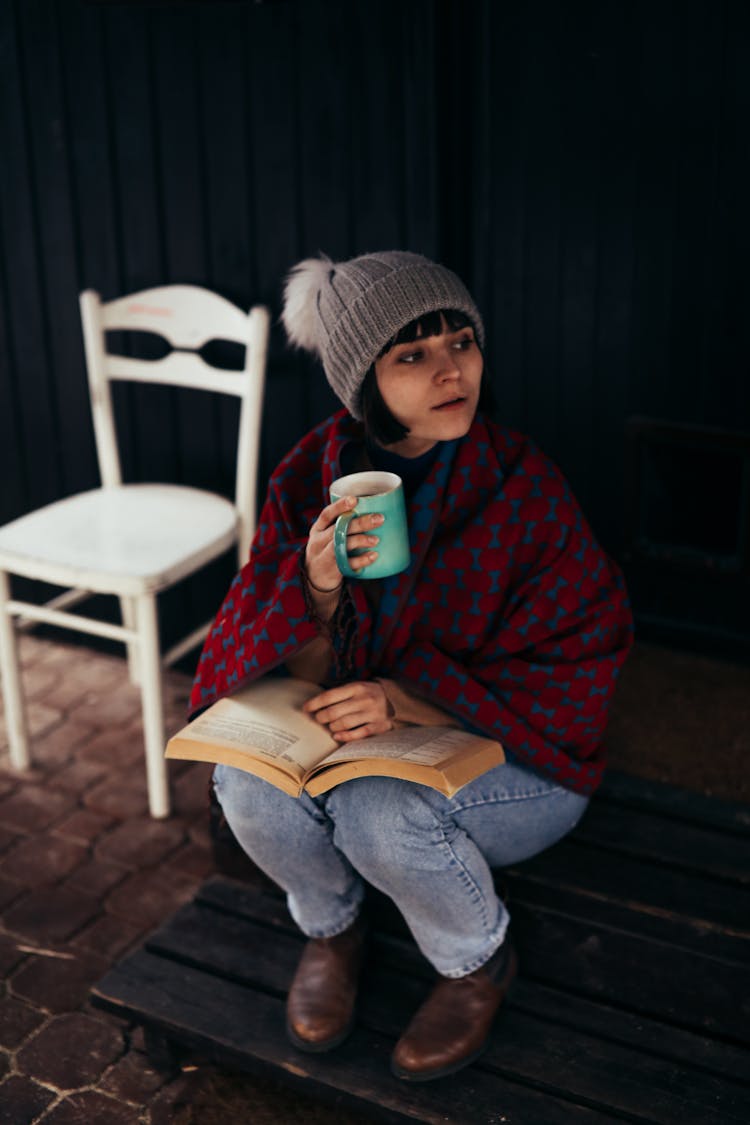 
A Woman Covered With A Blanket Having Coffee