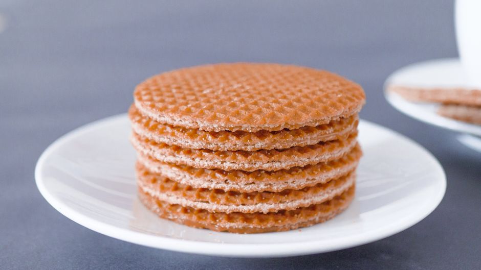 Stack of tasty stroopwafels on a white plate, perfect for a sweet snack.