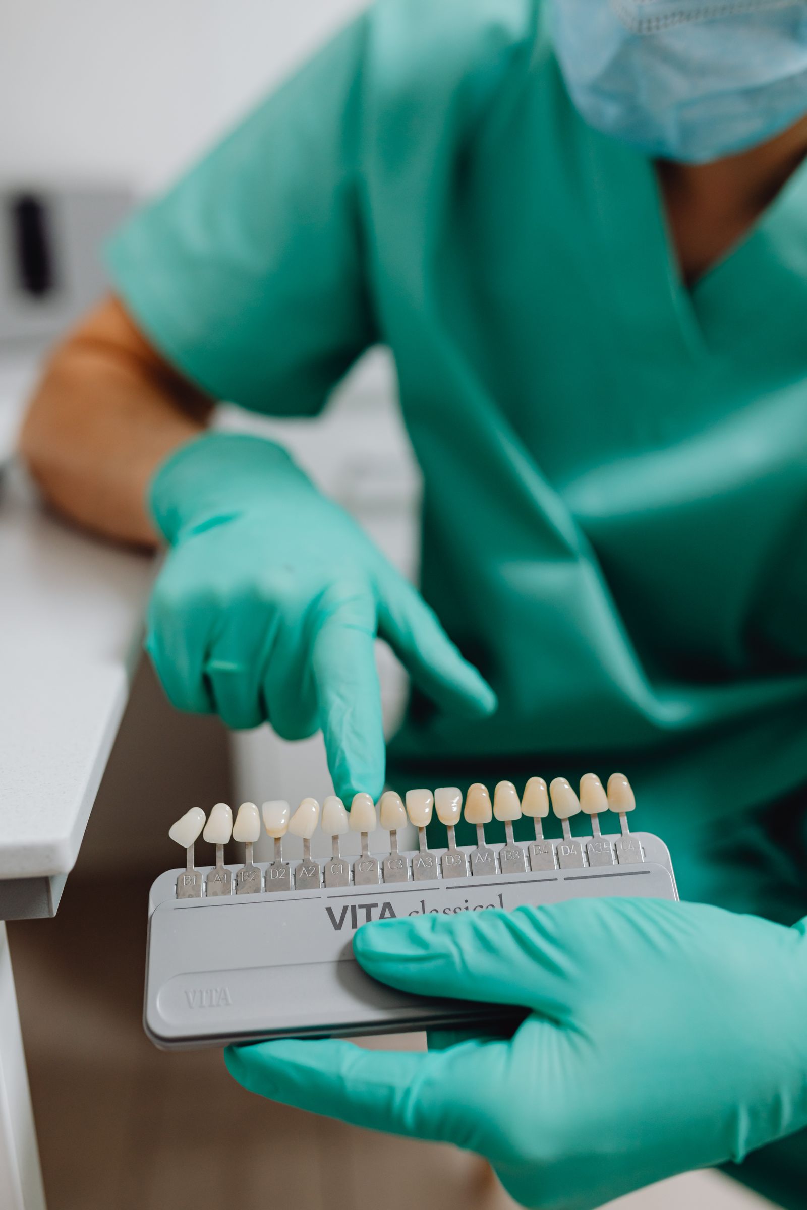 Dentist comparing a professional dental shade guide beside a patient's smile