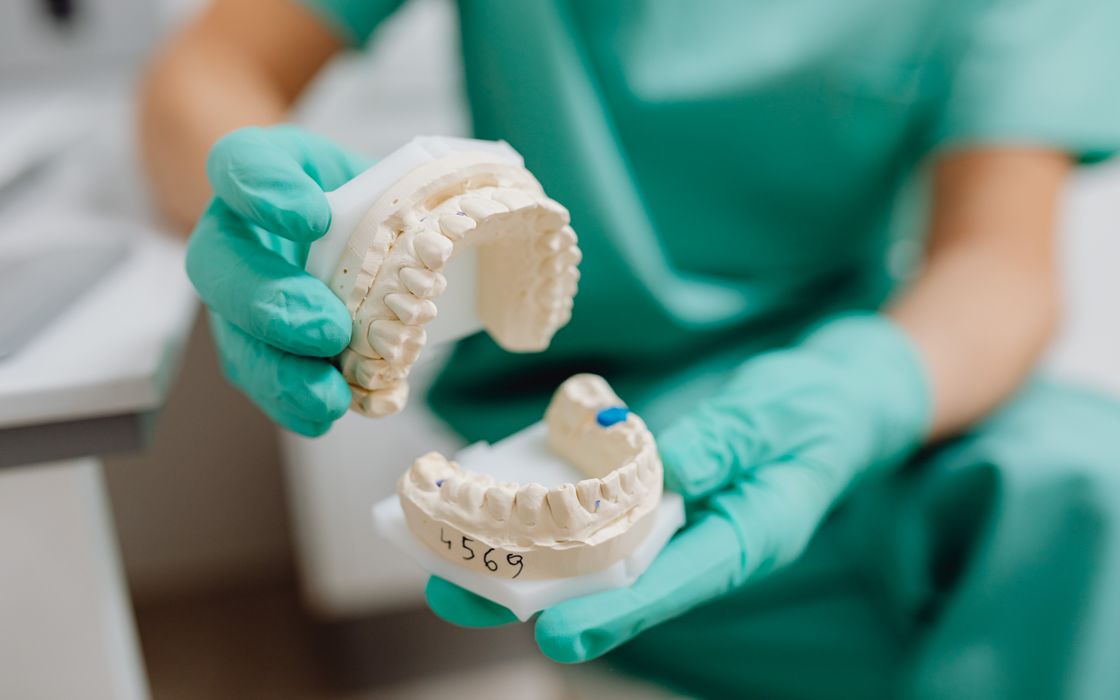 Close-up of a dental cast held with latex gloves in a clinical setting.