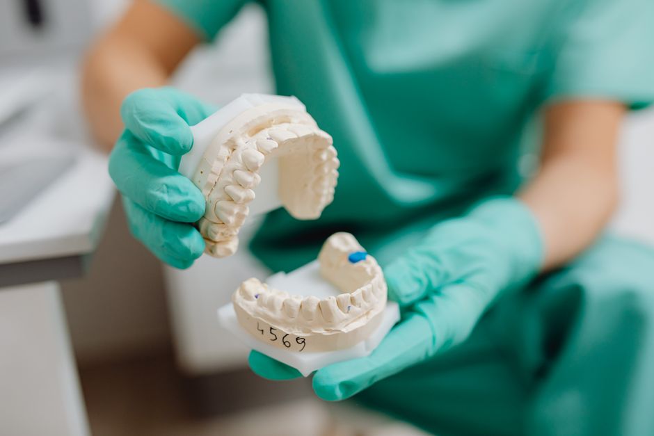 Close-up of a dental cast held with latex gloves in a clinical setting.