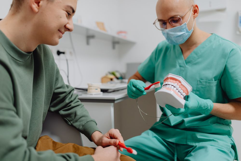 Professionista che spiega la corretta igiene orale con un modello dei denti