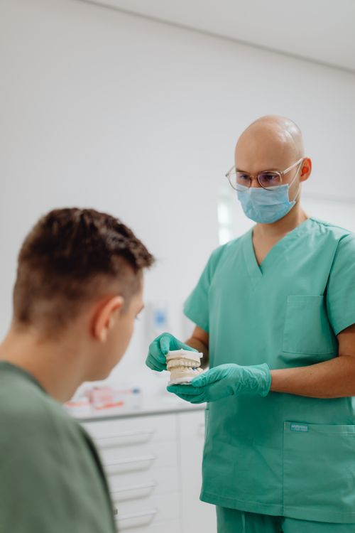 Free Dentist explaining dental care with a model to a patient in clinic. Stock Photo