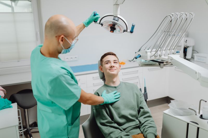 Dentista examinando paciente sob luz odontológica