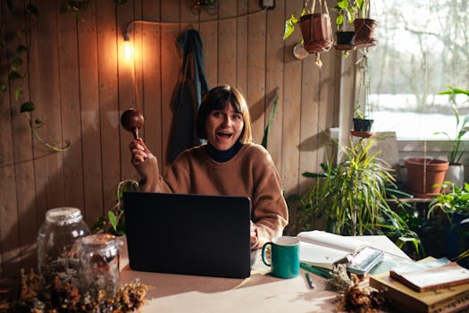 A woman happily working from home with a laptop and indoor plants.