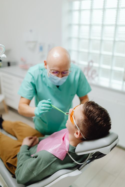 Free Dentist wearing mask and gloves examines patient in a dental clinic. Stock Photo
