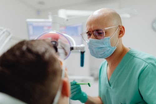 Free A dentist in protective gear examines a patient in a bright, modern dental clinic. Stock Photo