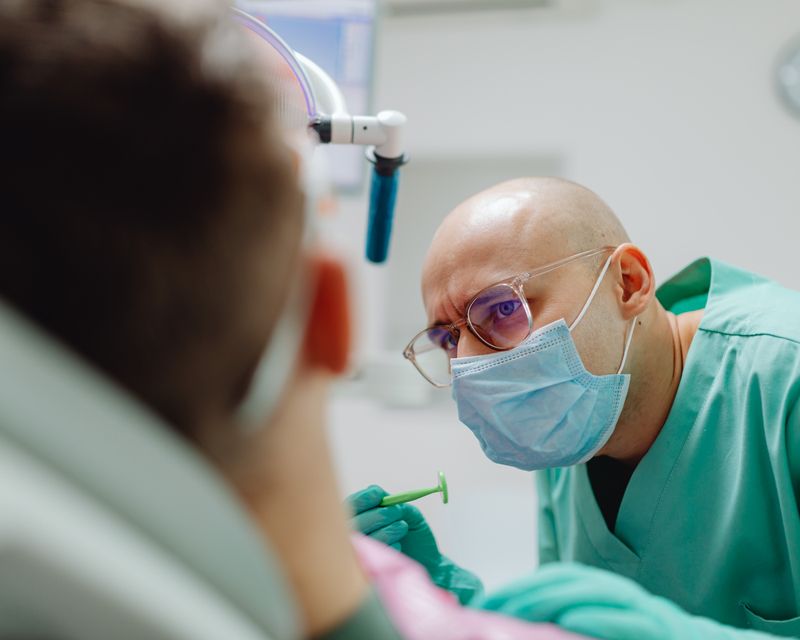 A dentist examining a patient's teeth with a mirror and good lighting