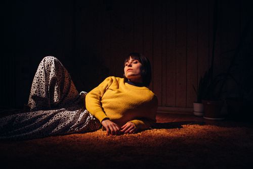 Free A woman in a yellow sweater reclines indoors, creating a warm, stylish scene. Stock Photo