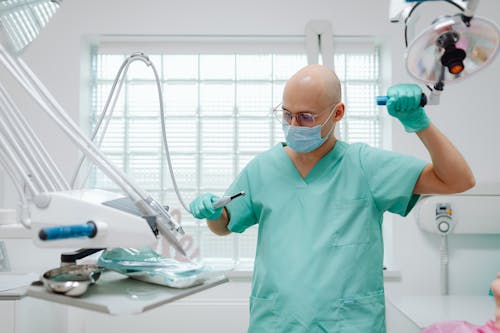 Man in Green Medical Scrub Suit Holding Medical Equipment