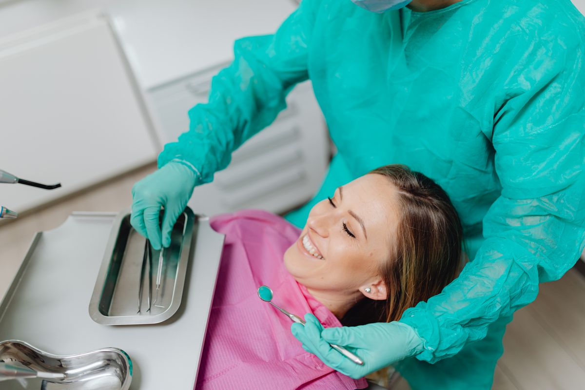 Woman smiling in a dental chair as her dentist prepares for an implant consultation