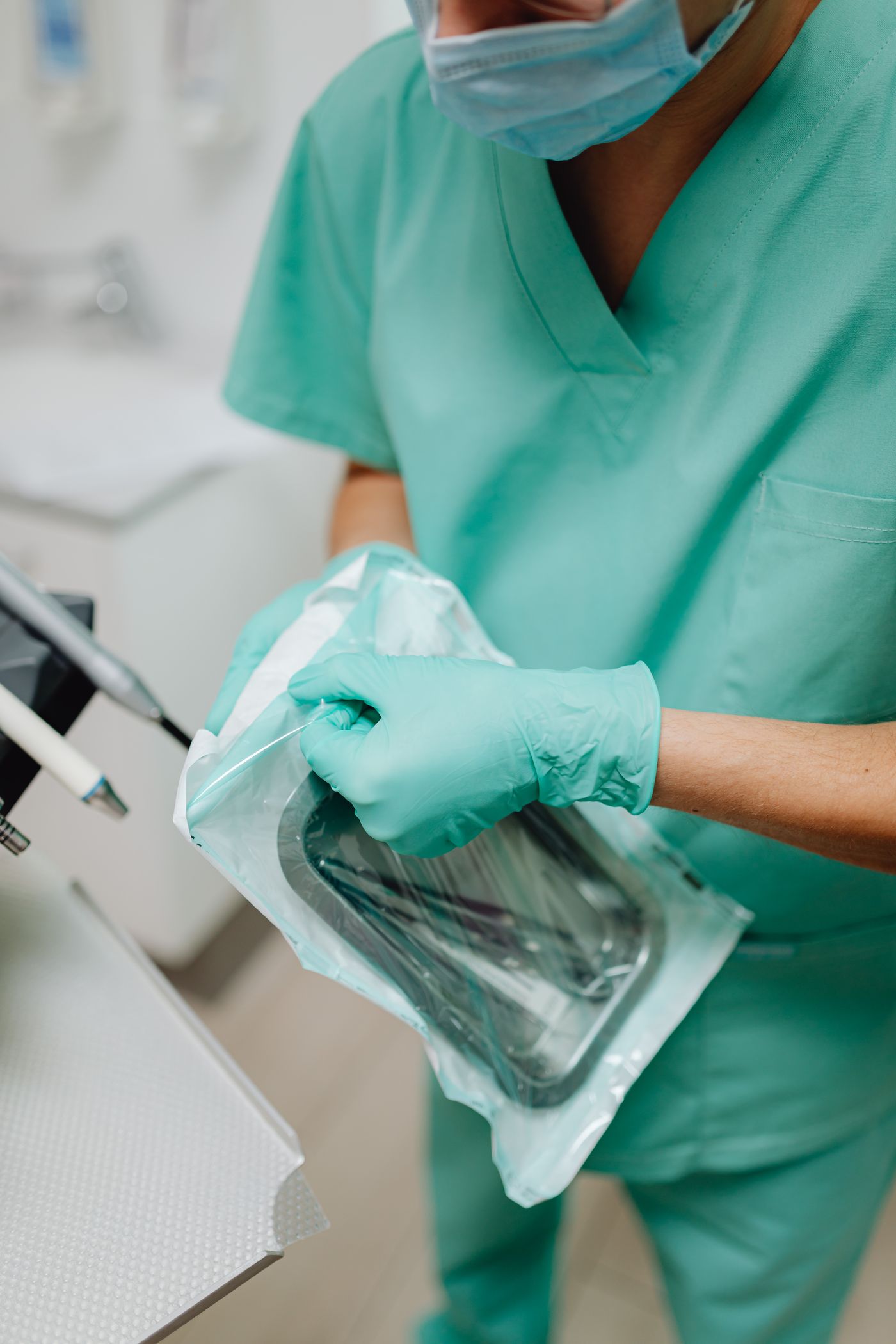 Gloved professional opening a sealed pack of sterilised instruments