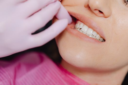 A dentist's gloved hand inspecting a patient's teeth during a check-up.