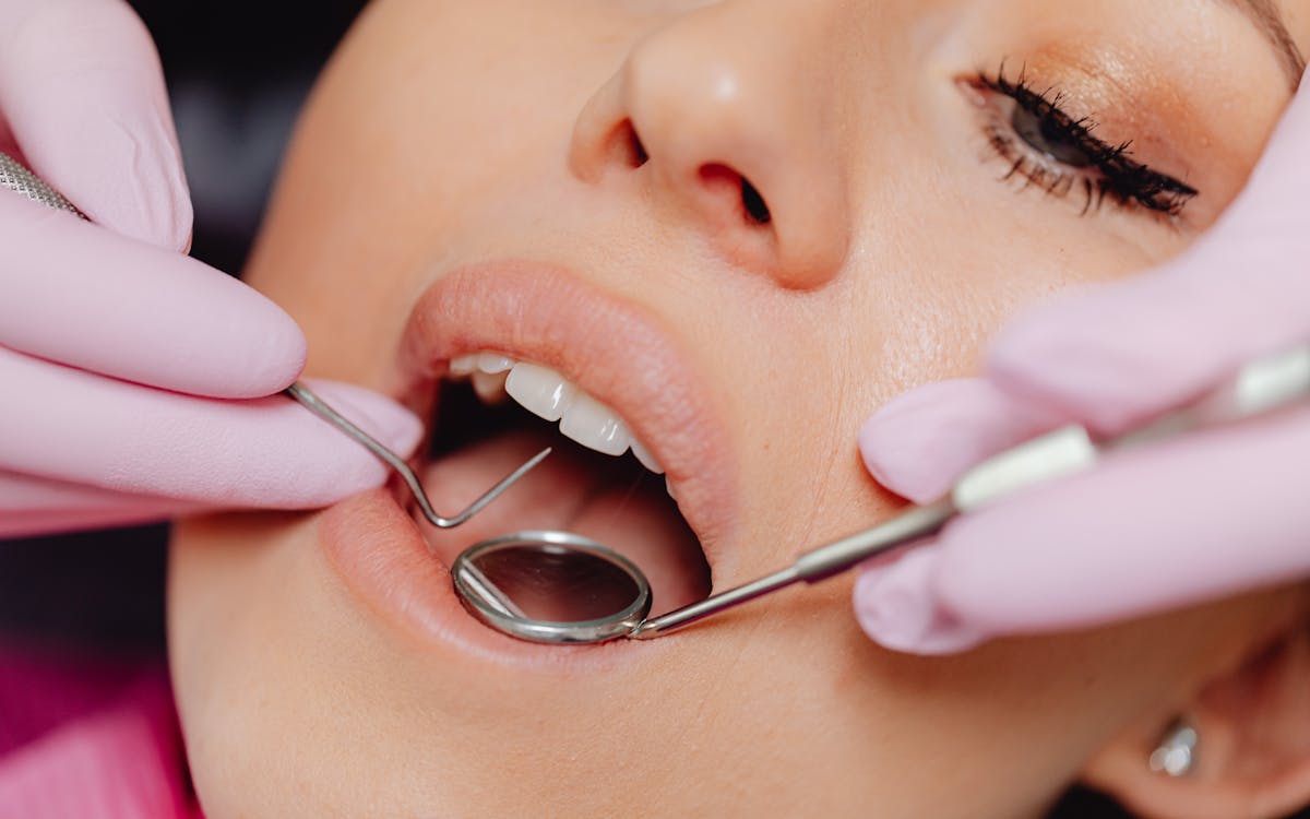 Close-up of a woman's dental checkup with a dentist using tools in a clinic.