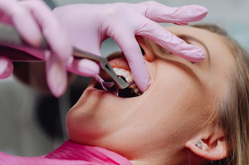 Photo of a Person with Pink Gloves Checking a Woman's Teeth