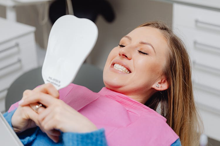 Smiling Woman In Dentist Chair Looking In Mirror 