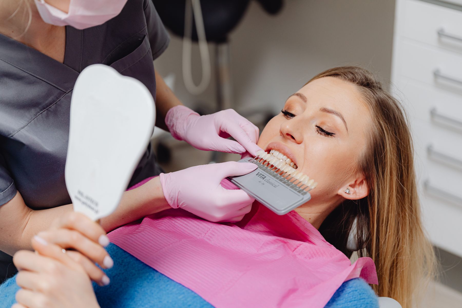 Dentist discussing tooth shade options with a smiling cosmetic dentistry patient in a bright dental clinic