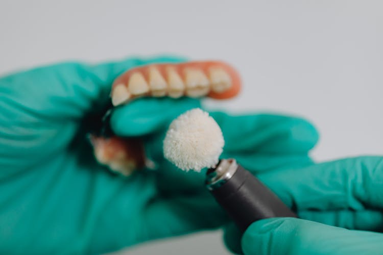 

A Close-Up Shot Of A Person Polishing Dentures