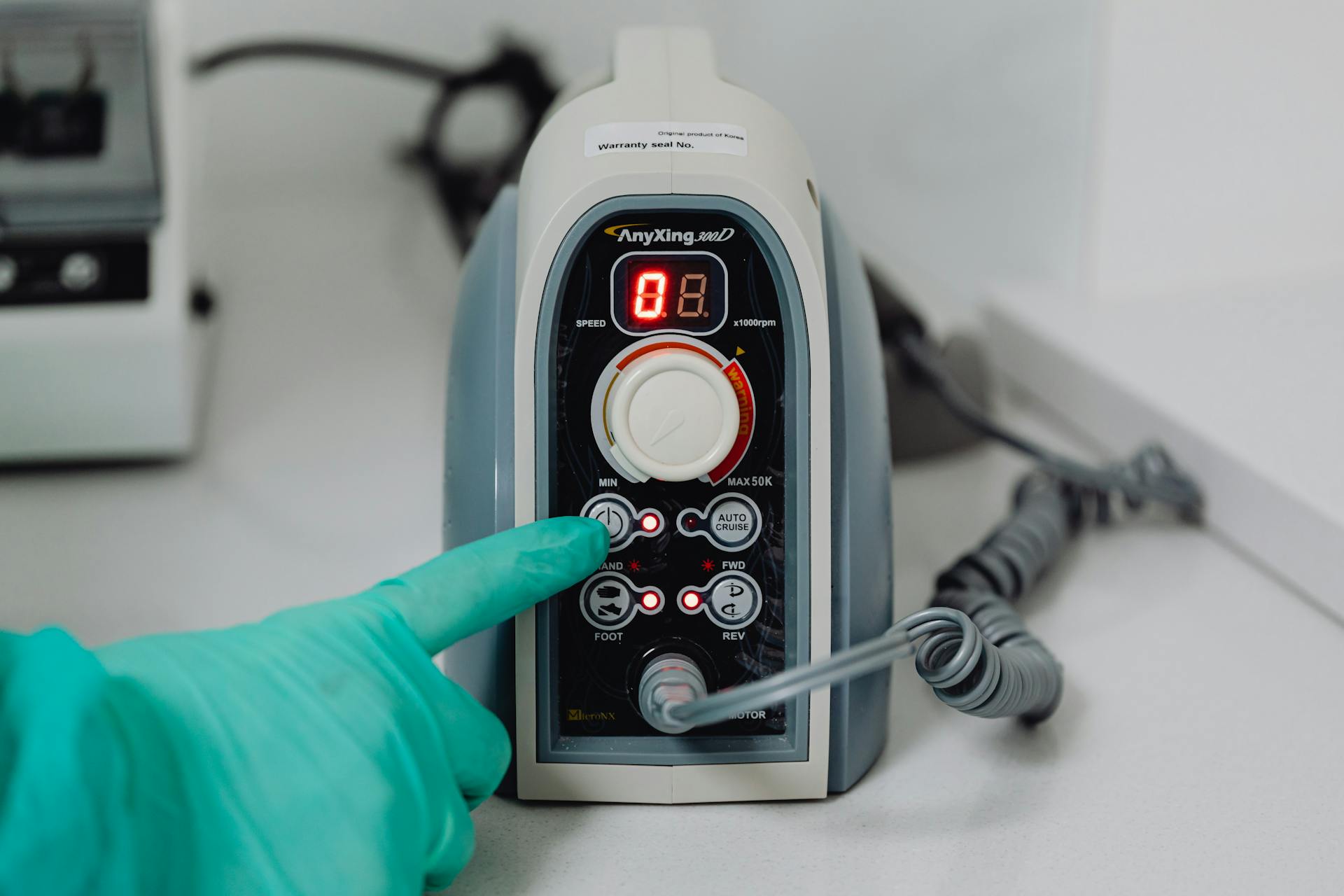 Close-up of a machine being operated in a medical setting with latex-gloved hand.