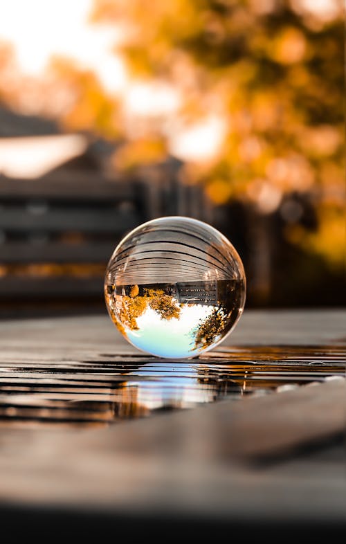 Clear Glass Ball on Brown Wooden Table