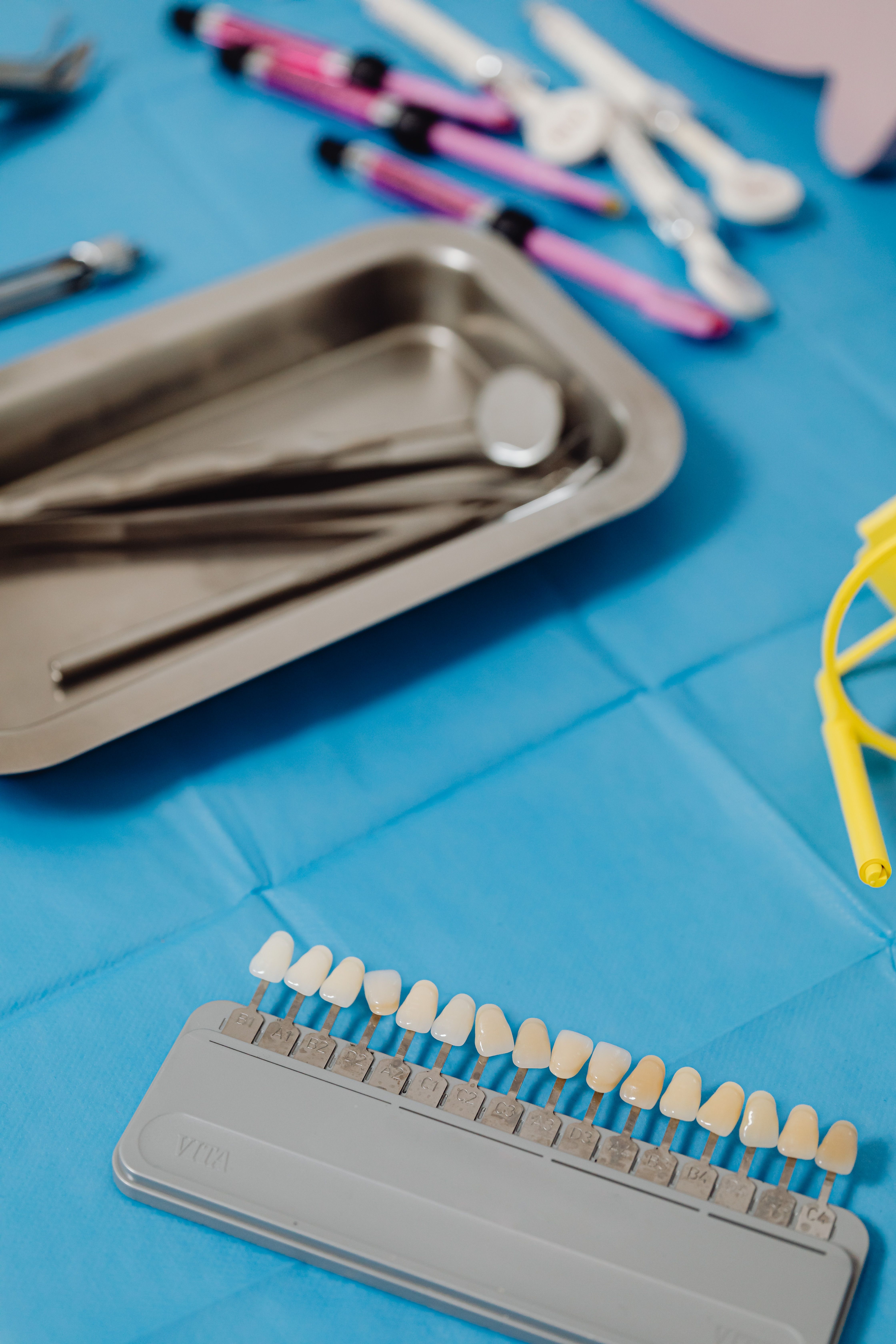 Close-up of a dental shade guide with tools on a blue cloth surface.