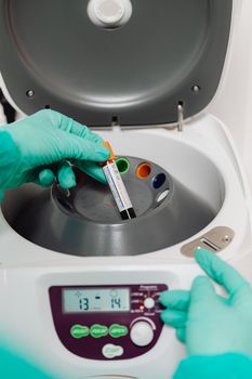Lab technician operates a centrifuge with a blood sample for testing. — photo by www.kaboompics.com