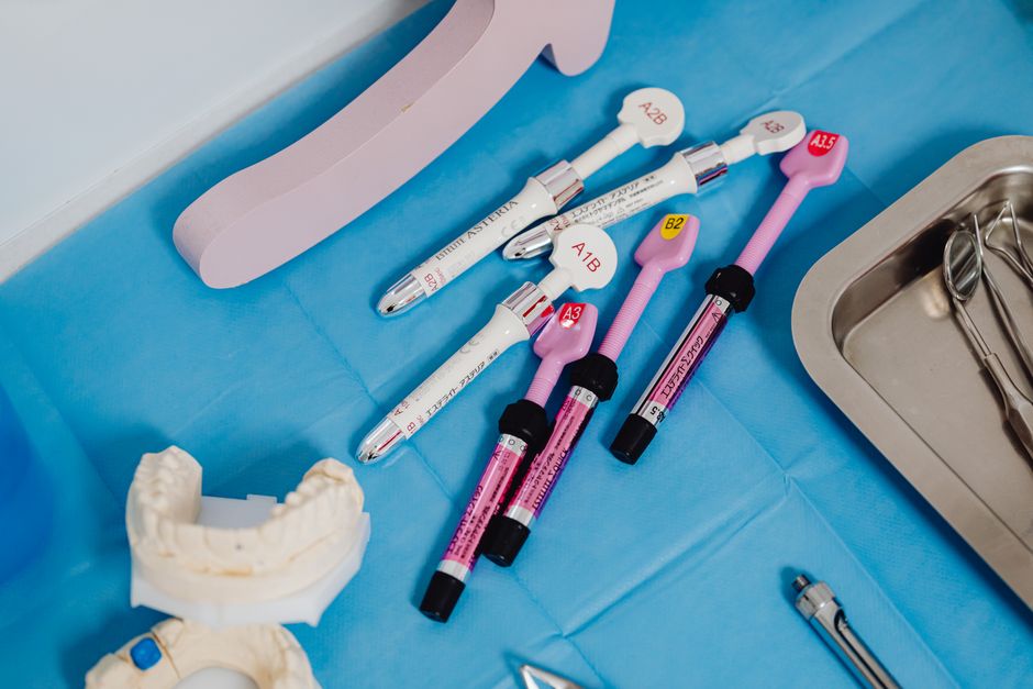 A detailed view of dental instruments and materials arranged on a sterile blue surface in a clinical setting.