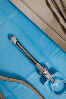 Close-up of a sterile surgical steel instrument on a blue drape in an operating room.