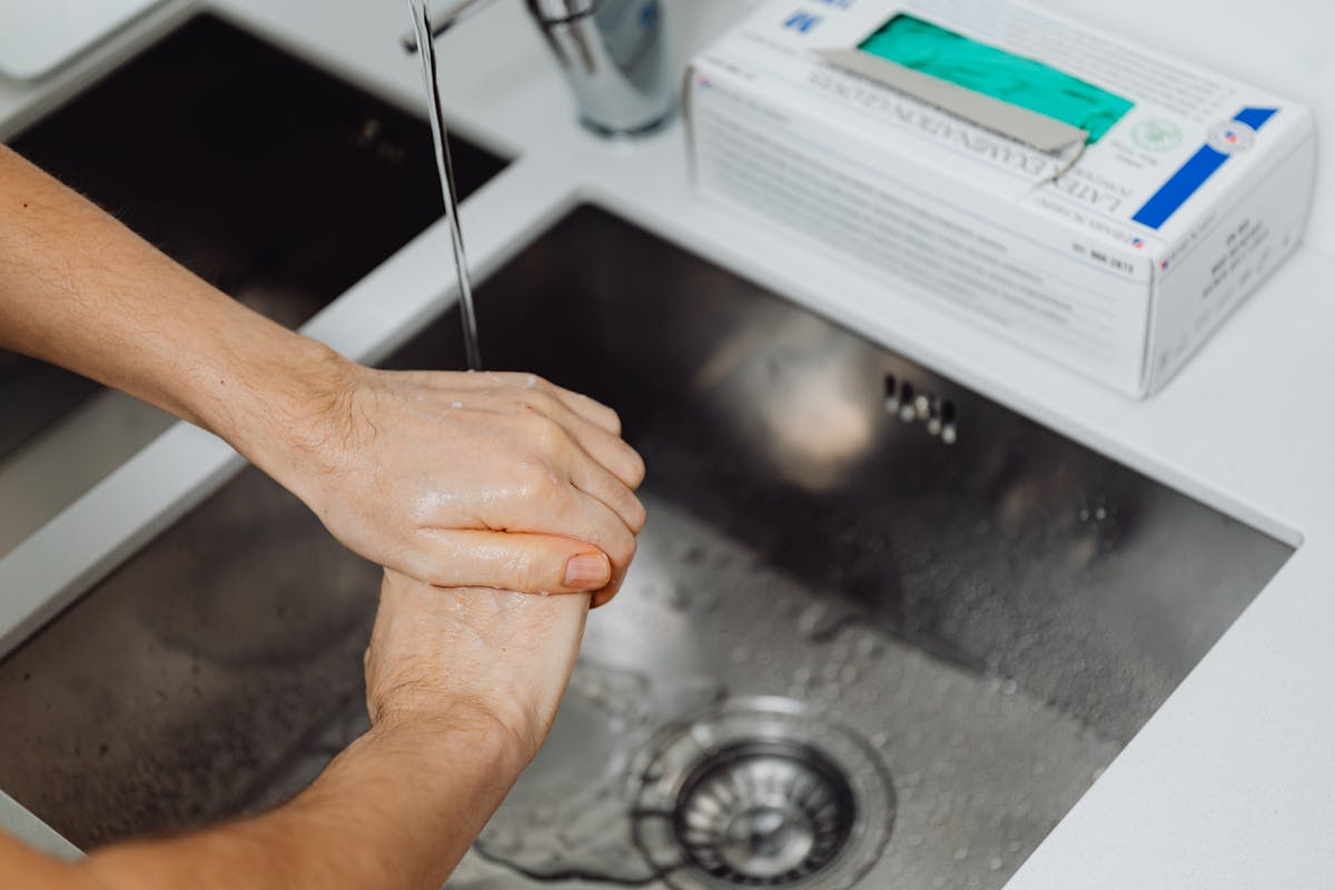 Primo piano di mani che sciacquano sotto un rubinetto d'acqua
