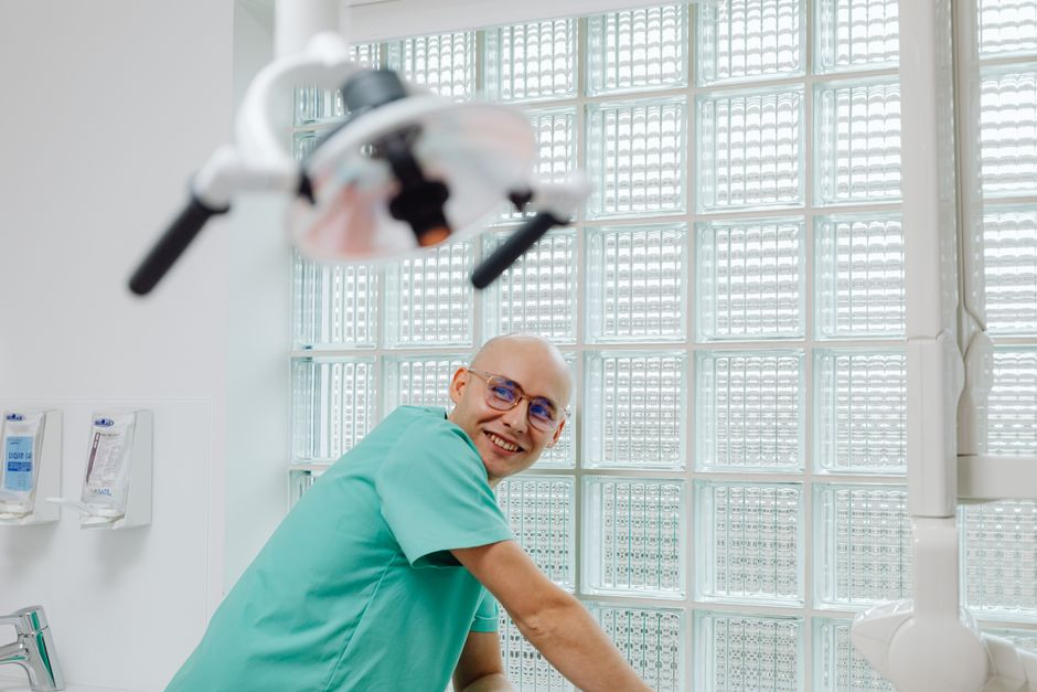 Cheerful dentist in green scrubs smiling in a contemporary dental office.
