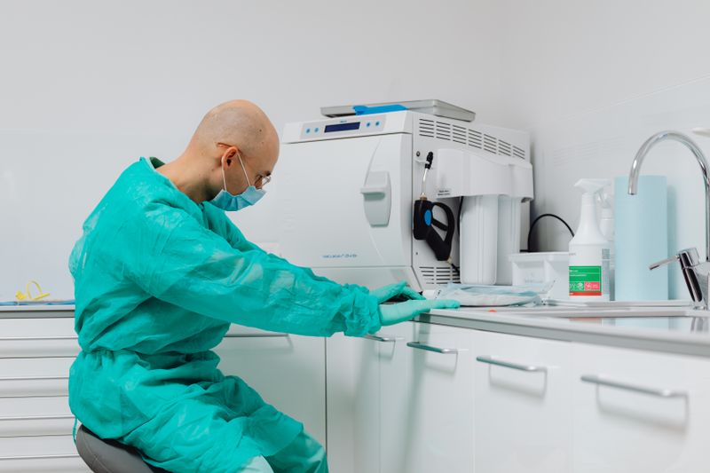 A hygienist in teal scrubs working at a clinic counter