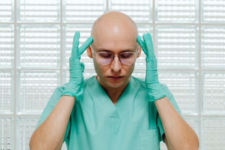 Doctor In Medical Uniform Touching Head