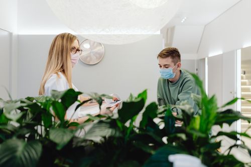 Free Reception area in a healthcare facility with masked staff and patients interacting indoors. Stock Photo