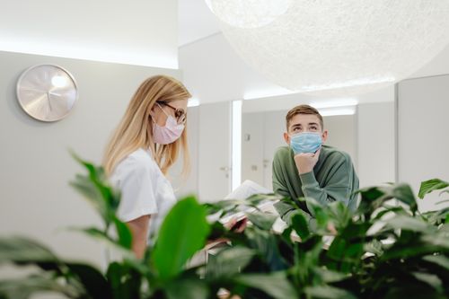 Free Nurse and patient wearing face masks in a modern clinic, enhancing safety. Stock Photo