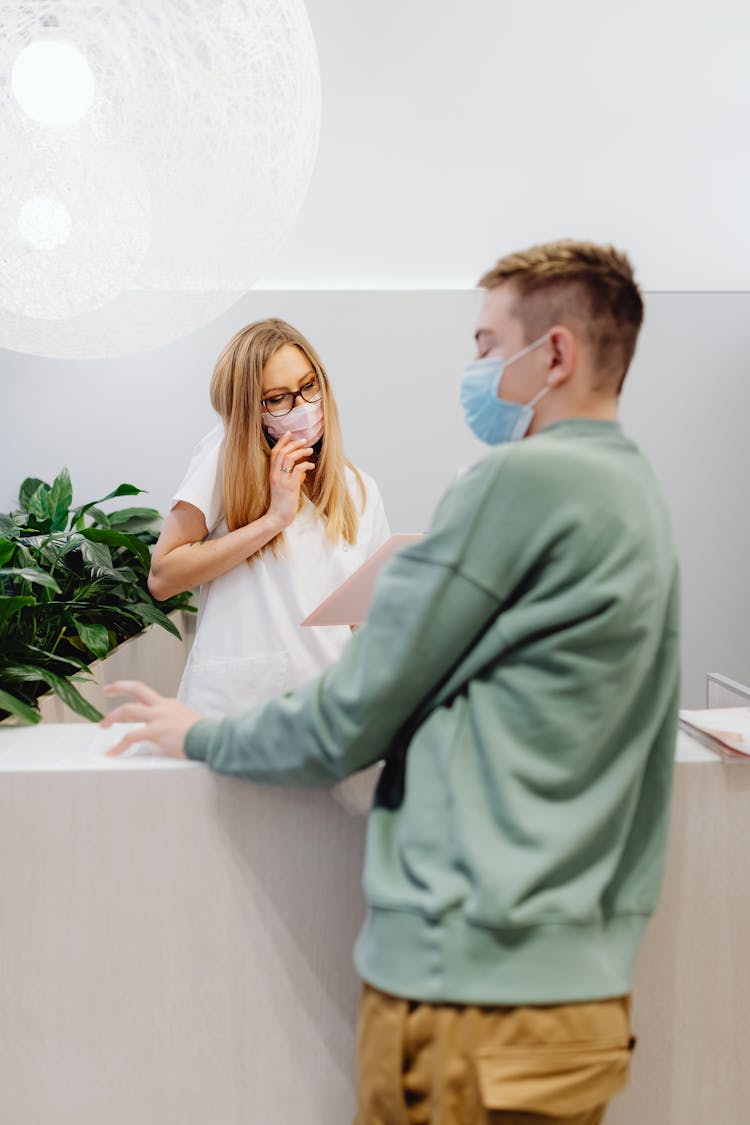 Man In Green Sweater Standing Near A Receptionist