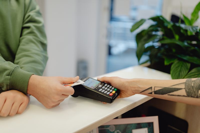 A close-up view of a contactless payment being made with a bank card over a payment terminal.