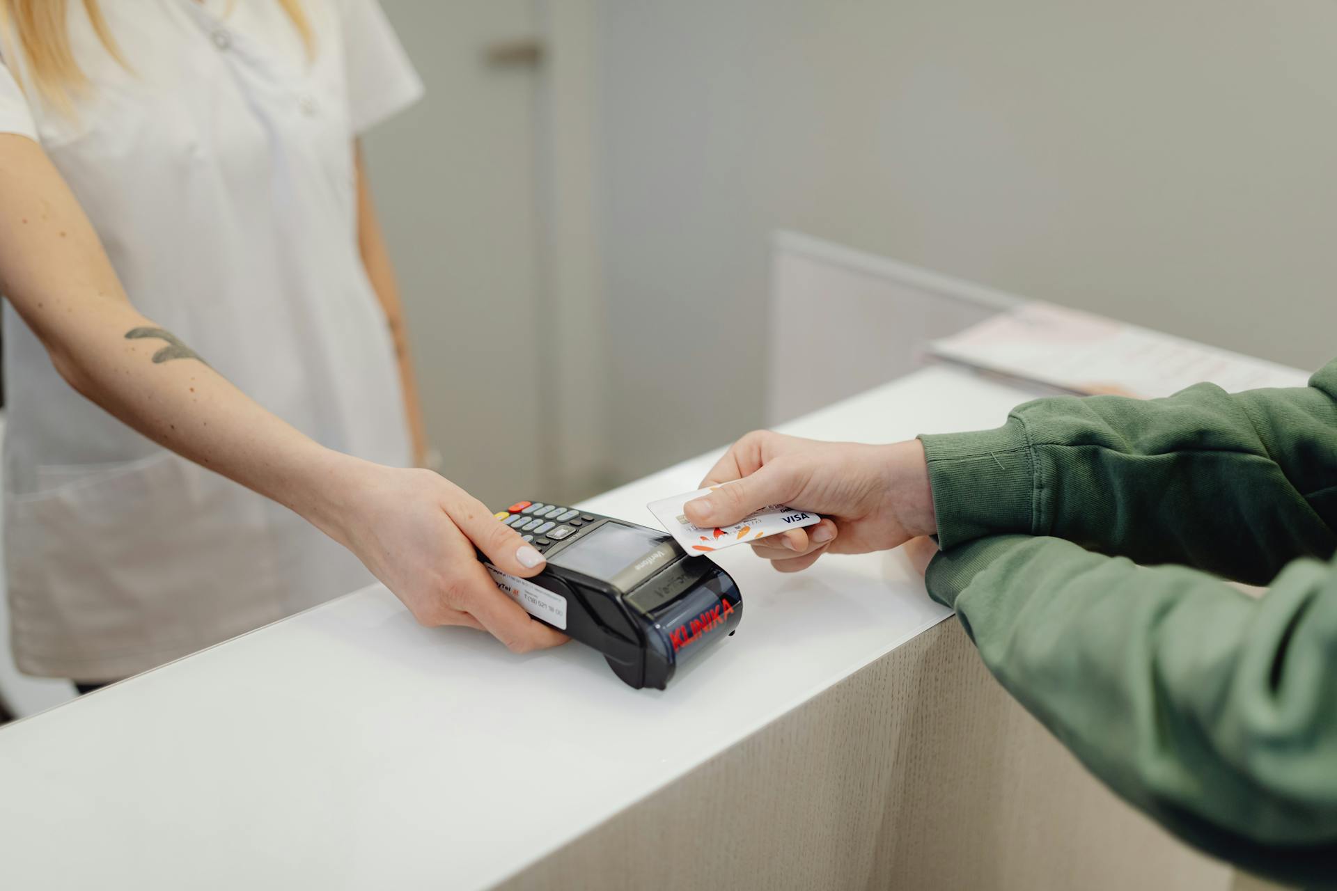 Person using a bank card for contactless payment at a modern checkout counter.