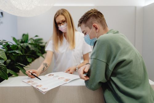 Free A man and a woman wearing face masks discuss medical information in a clinic setting. Stock Photo
