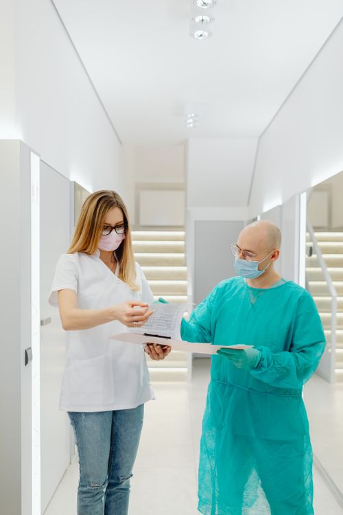 Free Medical practitioners in face masks discussing paperwork in a bright clinic interior. Stock Photo