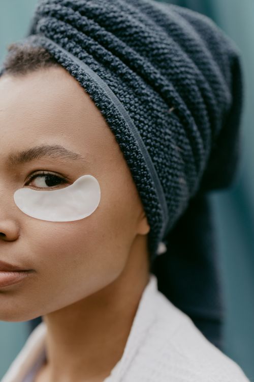 Free Close-up portrait of a woman with an eye patch and towel on head, showcasing skincare routine. Stock Photo