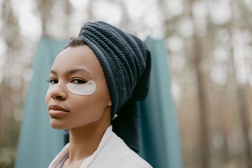 Free A serene portrait of a woman with eye patches and towel wrap, promoting self-care outdoors. Stock Photo