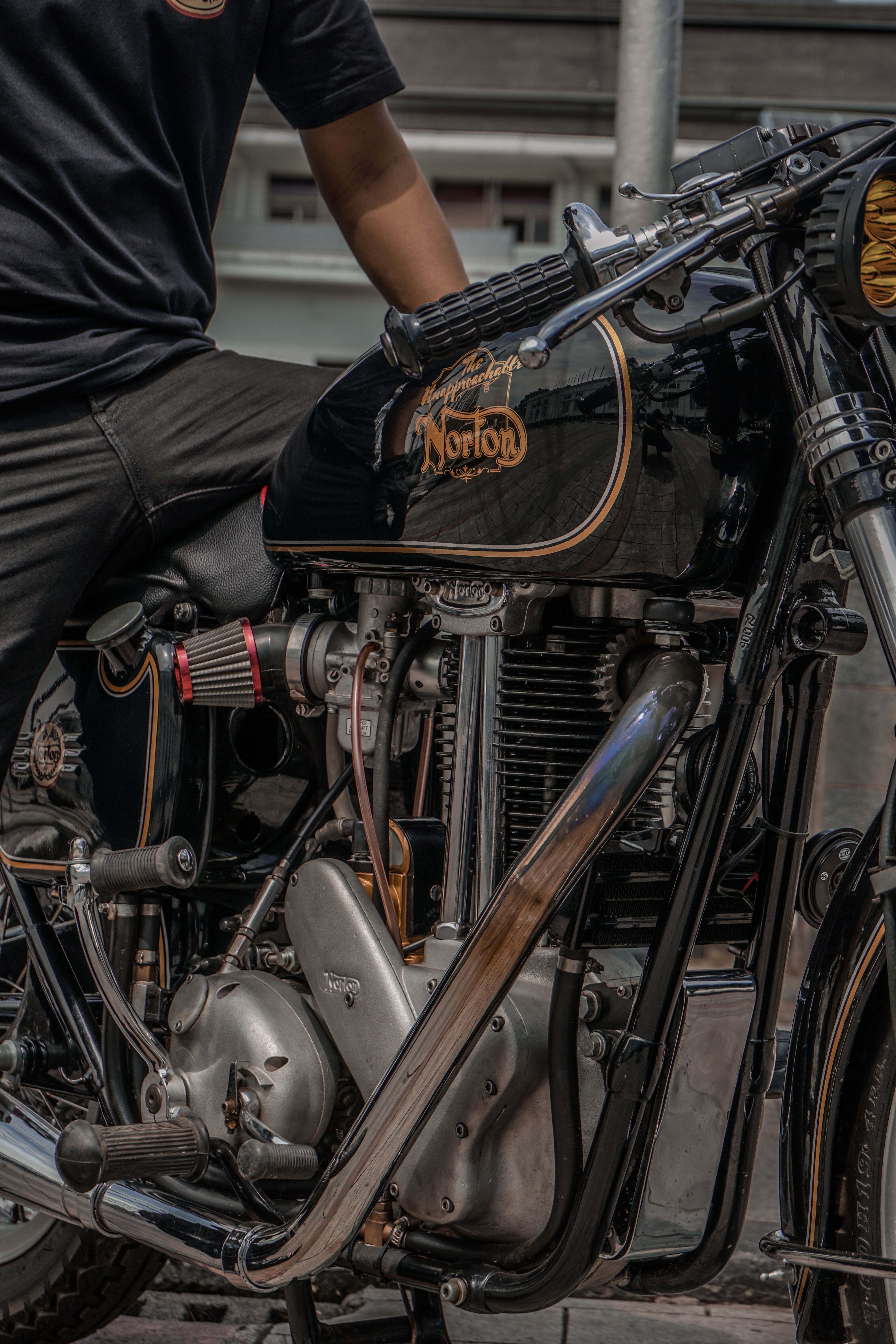 Close-up of a classic Norton motorcycle and a rider in an urban environment showcasing vintage design.