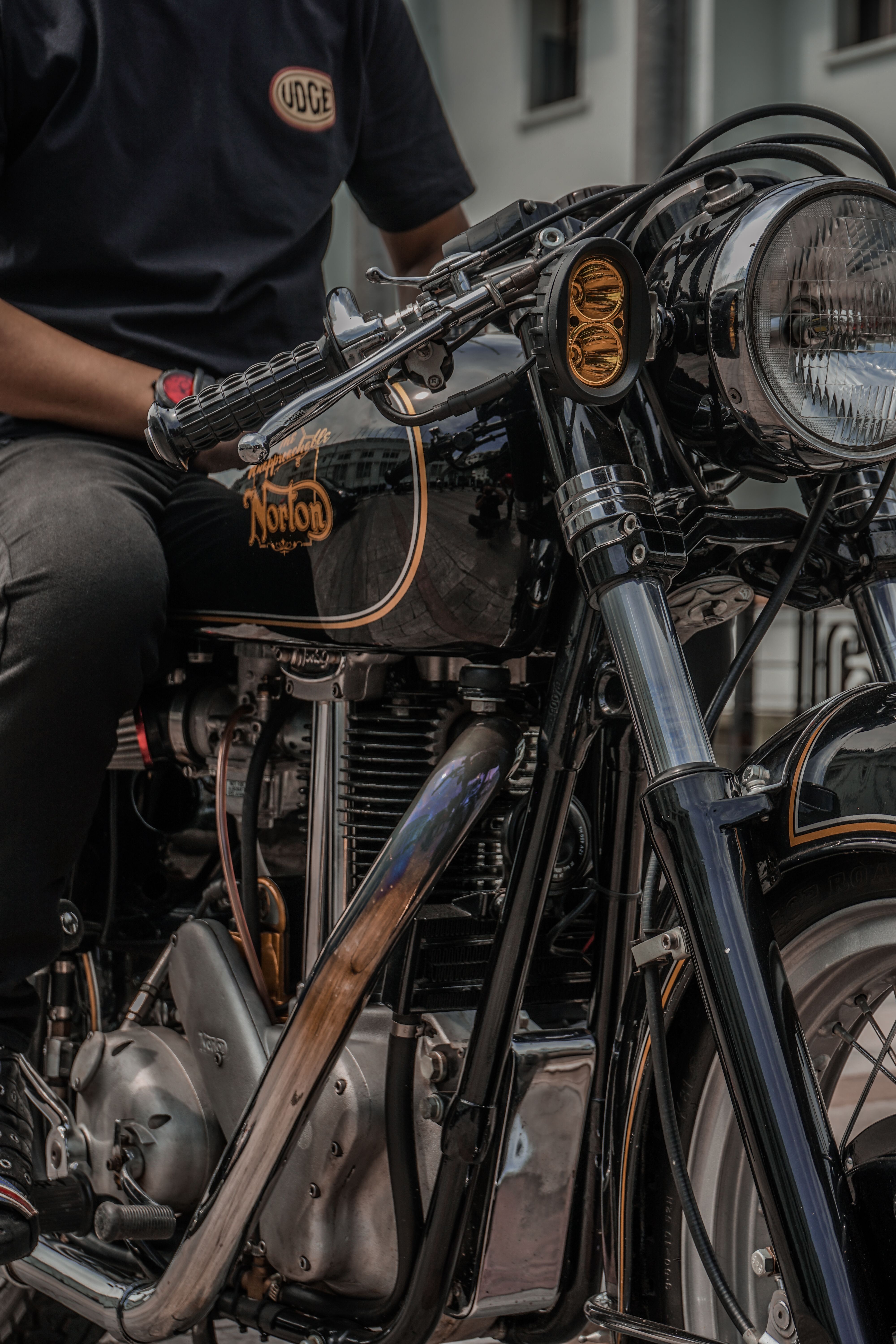 Close-up of a classic Norton motorcycle with a rider, showcasing vintage design.