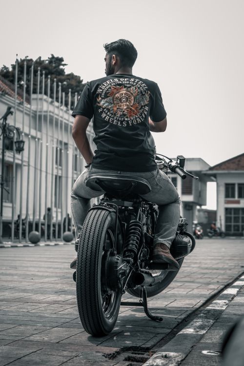 Free Back view of a biker sitting on a motorcycle in an urban setting. Stock Photo