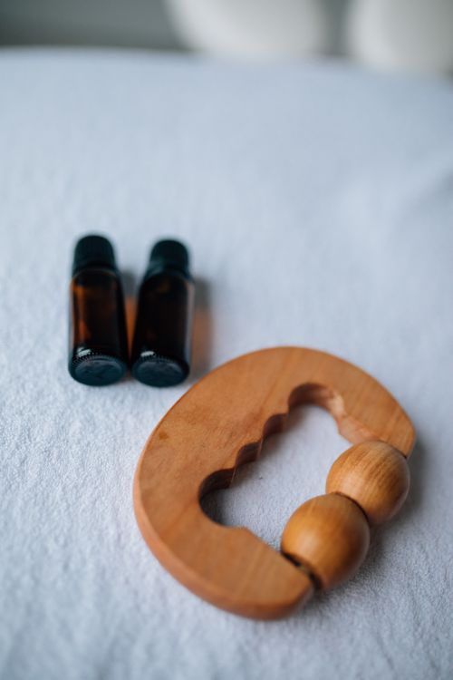 Free Close-up of essential oil bottles and a wooden massager on a soft surface. Stock Photo
