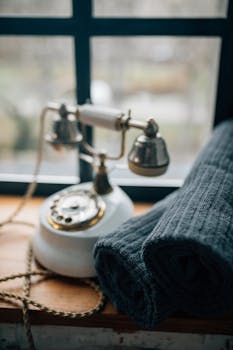 A vintage rotary telephone and fabric near a window, evoking a nostalgic feel.