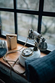 Classic white rotary telephone on window sill, exuding vintage charm and nostalgia.